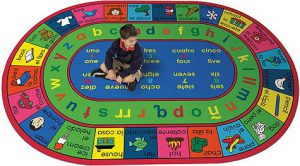 A child sitting on an educational rug with spanish and english words, letters and numbers