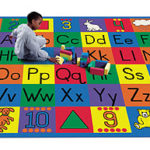 A child playing with blocks on a educational kids rug. This rug shows the alphabet in upper and lower case.