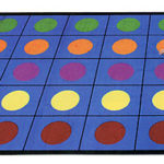 A kid sitting on a classroom rug with individual seating spaces with rows of multi colored circles