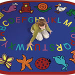 a girl kneeling on a rug with letters. This rug is blue with the alphabet around the center and whimsical animals around the edge.