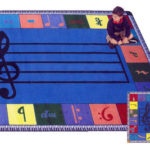 A child sitting on a blue educational kids rug with music notes.