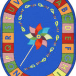 An oval educational kids rug with a pinwheel in the center and the alphabet around the edge.