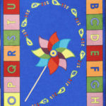 An educational kids rug with a pinwheel in the center and the alphabet around the edge.