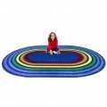A child sitting on an oval rug with rainbow colored rings around the rug.