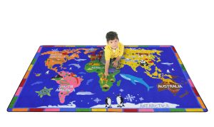 A child sitting on a kids rug containing a map of the world.